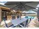 Outdoor dining featuring table with umbrella with a picturesque view of the swimming pool and backyard bar at 3437 Aspen Trl, Clearwater, FL 33761