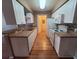 Galley kitchen features white appliances and cabinets, wood-style flooring, and tiled backsplash at 36137 Lake Chase Blvd # 102, Zephyrhills, FL 33541