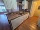 Kitchen features stainless steel sink, white cabinets, wood-style floors, and a view of the living space at 36137 Lake Chase Blvd # 102, Zephyrhills, FL 33541