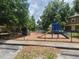 Community playground with slide and climbing structure amidst mature trees and fenced perimeter, great for outdoor activity at 36137 Lake Chase Blvd # 102, Zephyrhills, FL 33541