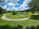 Picturesque view of a pond surrounded by lush greenery and a meandering walkway in a serene community setting at 36137 Lake Chase Blvd # 102, Zephyrhills, FL 33541