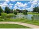 A pond featuring a fountain, lush greenery, and walkways in a tranquil community setting at 36137 Lake Chase Blvd # 102, Zephyrhills, FL 33541