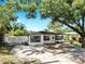 Well-maintained single-story home with black trim windows and a spacious driveway, complemented by lush trees at 4112 W Lawn Ave, Tampa, FL 33611