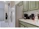 Practical kitchen space with stainless refrigerator, marble countertop, and sage colored cabinetry at 4522 Lisette Cir, Brooksville, FL 34604