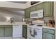 Kitchen with green cabinets, white appliances, and stylish backsplash at 4522 Lisette Cir, Brooksville, FL 34604