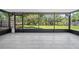 Enclosed lanai with tiled flooring, screens, black framing, and a beautiful view of the backyard and the lake beyond at 4639 Cabbage Palm Dr, Valrico, FL 33596