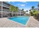 Community pool surrounded by palm trees and well-maintained landscaping with clear blue skies above at 751 Pinellas Bayway S # 104, St Petersburg, FL 33715