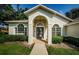 Inviting front entrance featuring arched doorway, decorative windows, and lush landscaping at 8604 Herons Cove Pl, Tampa, FL 33647