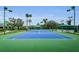 Well-lit tennis courts with green and blue surfaces, surrounded by lush landscaping and community amenities at 8604 Herons Cove Pl, Tampa, FL 33647