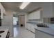 Efficient kitchen layout with white cabinetry, and views into breakfast nook and adjacent living areas at 8990 Antigua Dr, Seminole, FL 33777