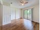 Bright bedroom featuring hardwood floors, ceiling fan, closet and sliding glass doors to a balcony at 22706 Gage Loop # 31, Land O Lakes, FL 34639