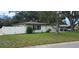 A cozy, well-kept house with a new white fence, lush green lawn and mature landscaping at 1027 Fountainhead Dr, Largo, FL 33770