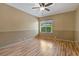 This bedroom has a ceiling fan, wood floors, and a window overlooking the yard at 1046 Middlesex Dr, New Port Richey, FL 34655