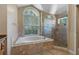 Elegant bathroom showcasing a soaking tub with tile surround and glass enclosed shower at 1046 Middlesex Dr, New Port Richey, FL 34655