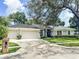 Charming single-story home with well-manicured lawn, mature trees, and a three-car garage at 11501 Norval Pl, Temple Terrace, FL 33617