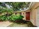 Home entrance features a red door and lush landscaping at 11783 102Nd Ave, Largo, FL 33778