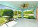 A screened in patio with ceiling fan overlooks the green, fenced backyard with view of lush trees and landscaping at 13116 Marathon Blvd, Port Charlotte, FL 33981