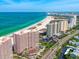 Stunning aerial view of beachfront condos along a pristine coastline with crystal-clear turquoise waters and vibrant city skyline at 1340 Gulf Blvd # 12A, Clearwater Beach, FL 33767