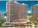 Exterior of a beachfront condominium featuring a tennis court, palm trees, and a parking area at 1340 Gulf Blvd # 12A, Clearwater Beach, FL 33767