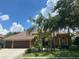 Beautiful single-story home with a brown roof, well-manicured landscaping and multiple palm trees in the front yard at 1353 El Pardo Dr, Trinity, FL 34655