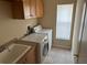Well-equipped laundry room with sink, cabinets, tile floor, and included washer and dryer at 1353 El Pardo Dr, Trinity, FL 34655