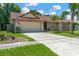 Inviting tan single story home with a well-manicured front yard and a spacious two-car garage at 1604 Dusty Rose Ln, Brandon, FL 33510