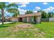 Attractive single story home with verdant lawn and mature tropical landscaping on a beautiful sunny day at 1604 Dusty Rose Ln, Brandon, FL 33510