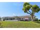 Rear exterior view showcases the screened lanai, deck, lush lawn, and tranquil waterfront setting at 1717 Danbury Dr, Sun City Center, FL 33573