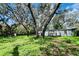 A charming light-blue single-story home nestled among mature trees, offering a tranquil setting and appealing curb appeal at 1821 Weekend Ln, Odessa, FL 33556