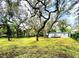 Charming home with light blue siding and a lush lawn, surrounded by mature trees and a welcoming deck at 1821 Weekend Ln, Odessa, FL 33556