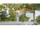 Aerial view of neighborhood showcasing a gray-roofed Bradenton home amidst trees, with street access and nearby properties at 1826 2Nd E Ave, Bradenton, FL 34208