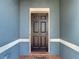 Inviting front door with a dark finish and a brick-tile entryway, set against a blue textured exterior at 18339 Fish Loop, Land O Lakes, FL 34638