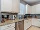 Modern kitchen featuring granite countertops, gray backsplash, stainless steel dishwasher and white cabinets at 18339 Fish Loop, Land O Lakes, FL 34638