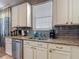 Modern kitchen featuring granite countertops, gray backsplash, stainless steel dishwasher and white cabinets at 18339 Fish Loop, Land O Lakes, FL 34638