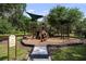 Community playground with modern play structure, mature trees, shade coverings and safety fencing at 19259 Mossy Pine Dr, Tampa, FL 33647