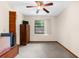 A simple, carpeted bedroom with a ceiling fan and a dark wood accent door at 2319 Canfield Dr, Spring Hill, FL 34609