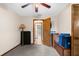 A simple, carpeted bedroom with a ceiling fan and a dark wood accent door at 2319 Canfield Dr, Spring Hill, FL 34609