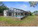 An enclosed screened-in pool, backyard with a grassy area, and partial views of the home's exterior at 2319 Canfield Dr, Spring Hill, FL 34609