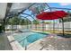 A screened-in pool with a hot tub, lit by string lights, and a red umbrella offering shade at 2353 Eastwood Dr, Clearwater, FL 33765