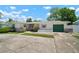 Single-story home with green garage door, brick accents, and a well-manicured front yard with mature trees at 2502 Tropical Shores Se Dr, St Petersburg, FL 33705
