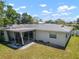 A view of the rear of a white home featuring a screened porch and spacious yard on a sunny day at 2502 Tropical Shores Se Dr, St Petersburg, FL 33705