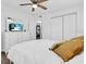 White dresser with a TV above, next to a bedroom bed with golden pillows and white bedding at 296 Huntington Dr, Largo, FL 33771