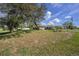Expansive front lawn with mature trees surrounding a charming single-story home at 3009 Ainsworth Ave, Spring Hill, FL 34609