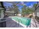 Screened-in pool area with gray patio and surrounding landscaping at 3009 Ainsworth Ave, Spring Hill, FL 34609