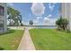 Expansive backyard with lush grass and a walkway leading to a community pool with lake access at 3127 W Sligh Ave # 101C, Tampa, FL 33614
