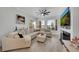 Bright living room featuring a large sectional sofa, ceiling fan, fireplace and serene views from the window at 3127 W Sligh Ave # 101C, Tampa, FL 33614