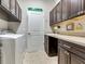 Well-equipped laundry room with custom cabinets, granite countertops, sink, and modern washer and dryer at 3503 Graycliff Ln, Brandon, FL 33511