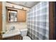 Compact bathroom features a vanity sink, toilet, and shower with a blue and gray patterned shower curtain at 35045 Cynthia Ave # 35945, Zephyrhills, FL 33541