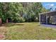 View of the grassy backyard and enclosed porch, offering an ideal space for outdoor activities at 3733 Mendocino St, New Port Richey, FL 34655