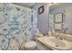 Updated bathroom with a decorative blue and white shower curtain and marble vanity at 3733 Mendocino St, New Port Richey, FL 34655